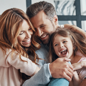 A small family laughing on a couch