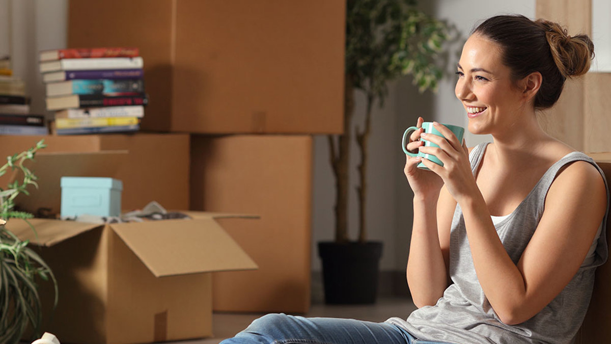 A young woman taking a break surrounded by moving boxes.