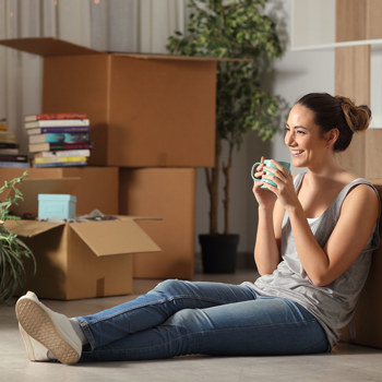 A women smiling while sitting by her move in boxes.
