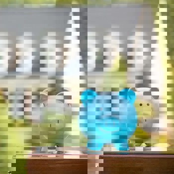 A piggy bank in front of a dream house.