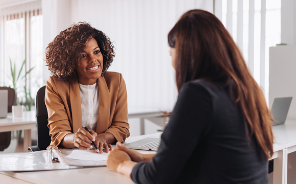 A smiling insurance agent meeting with a client in a brightly lit office