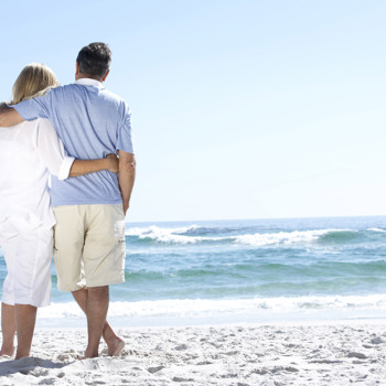 A couple staring out at the waves on the beach.