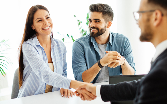 A young couple shaking hands with a mortgage originator.