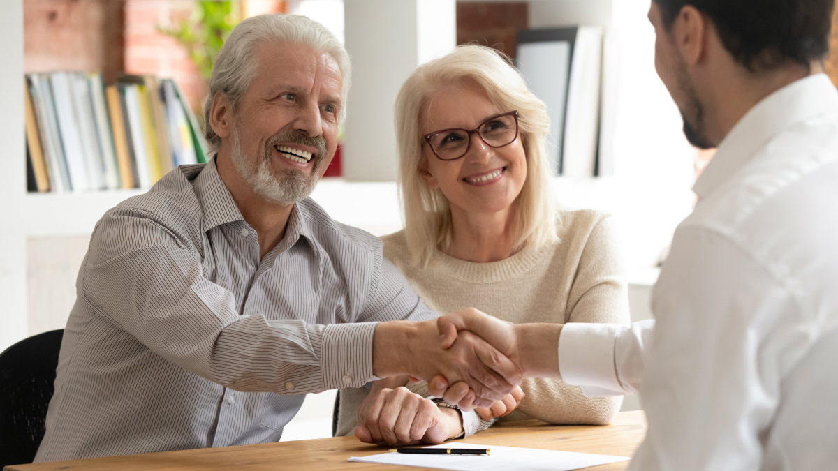 A smiling older couple excitedly meeting with an advisor.