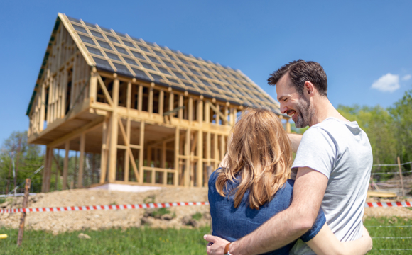 A young couple looking at their new home being built on a beautiful plot of land.