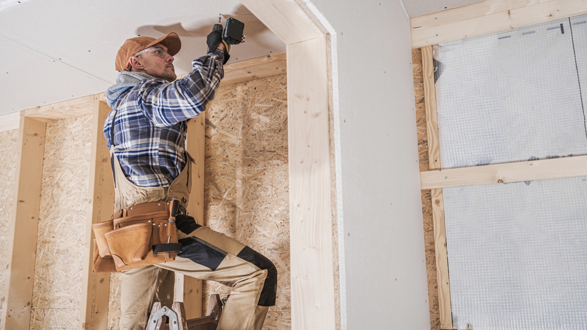 A construction worker or home owner working on a ladder inside a roughed in home