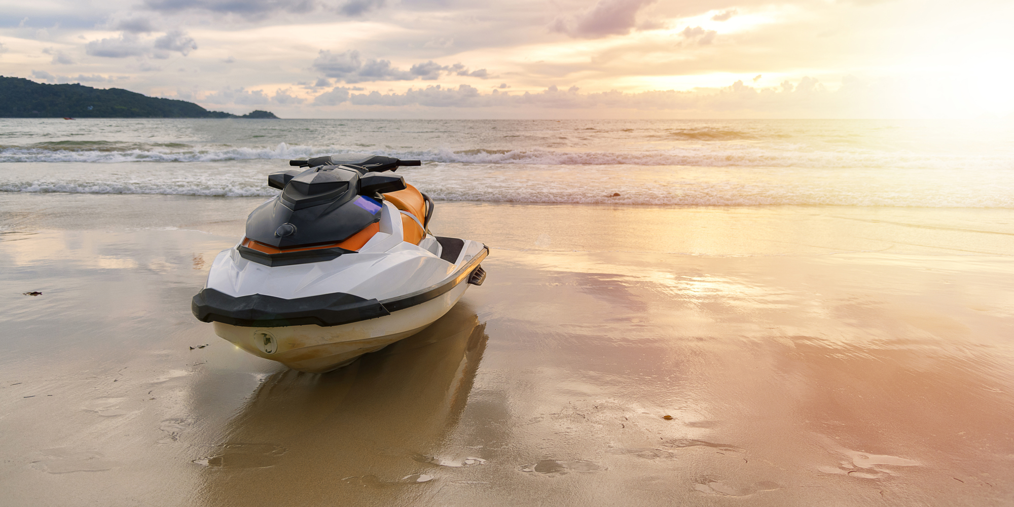 A parked waverunner on the beach at sunset.