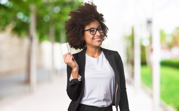 A smiling woman holding a credit card playfully