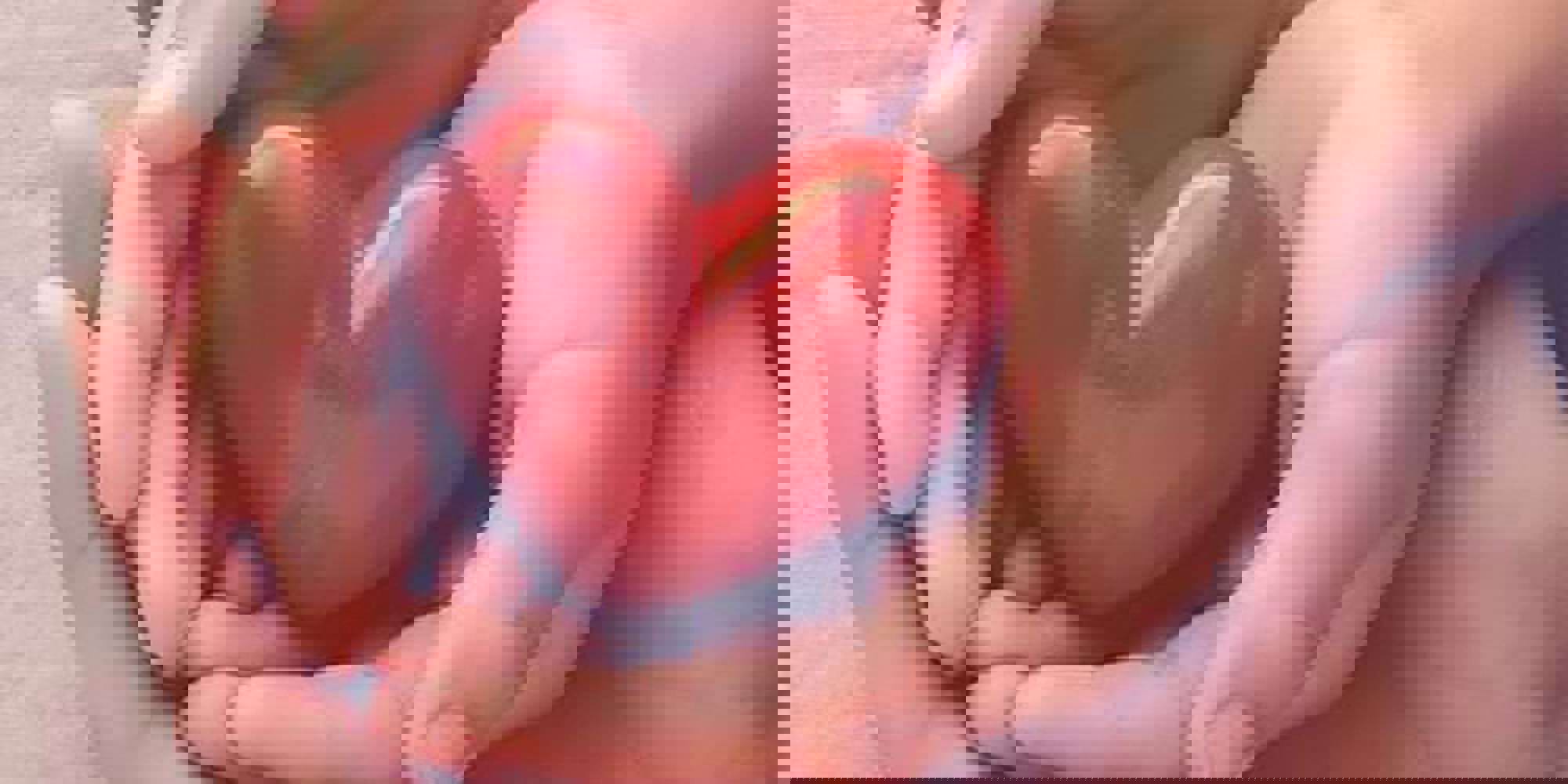 Closeup of hands holding a plastic red heart