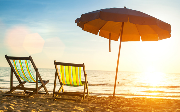 Two brightly colored beach chairs on a tropical beach.