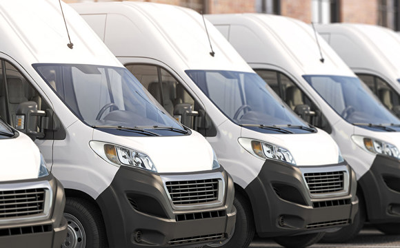A row of white delivery vans outside a shipping center
