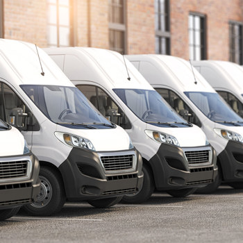 A row of white delivery vans outside a shipping center