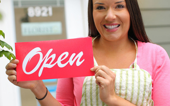 A small business owner outside her shop, smiling