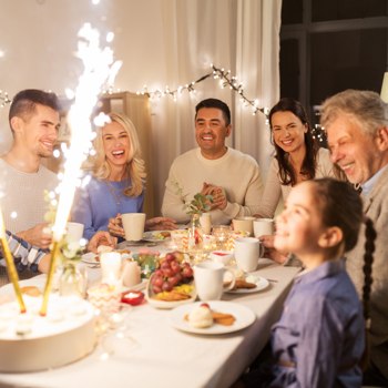 A family celebrating a birthday around a table with sparklers lit.