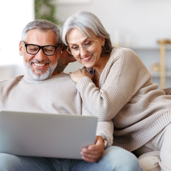 An older couple looking at their laptop together