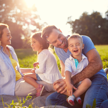 A family hanging out in the grass on a sunny day.