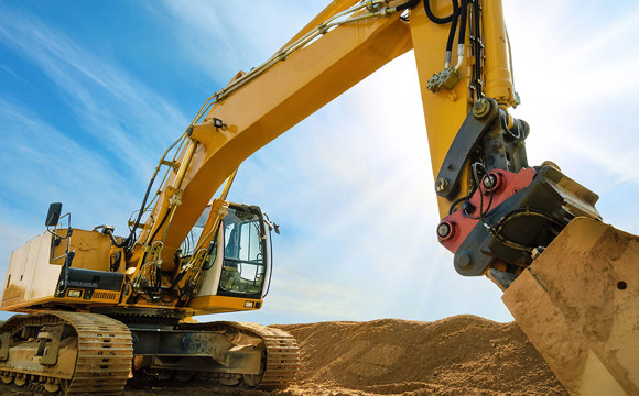 An excavator silhouetted against a blue sky