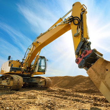 An excavator silhouetted against a blue sky