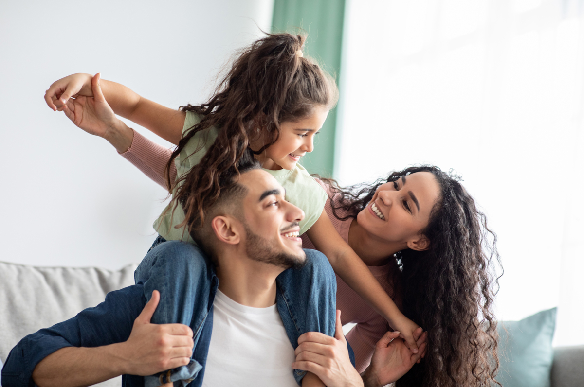 A daughter on her father's shoulders with her mom right behind them.
