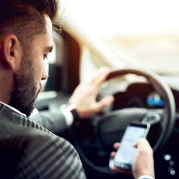 Man sitting in his car using his phone.
