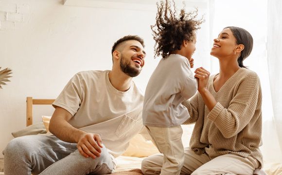 A couple playing with their child jumping on the bed
