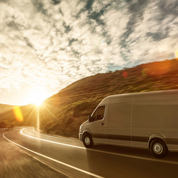 A commercial van on the highway at sunset