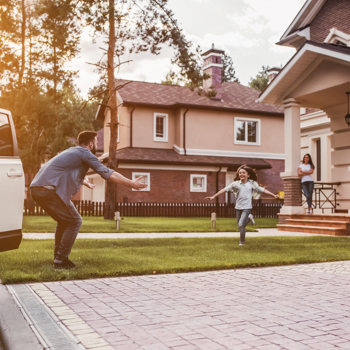 A kid running towards their dad who just arrived home